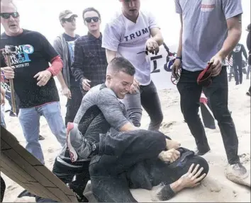  ??  ?? A supporter of President Donald Trump, center, clashes with an anti-Trump protester, bottom center, Saturday in Huntington Beach, Calif. Violence erupted when a march of about 2,000 Trump supporters at Bolsa Chica State Beach reached a group of about...