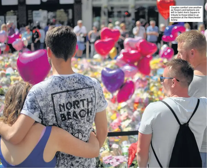  ??  ?? Couples comfort one another as flowers and balloons are left in Saint Ann’s Square in tribute to those killed in an explosion at the Manchester Arena