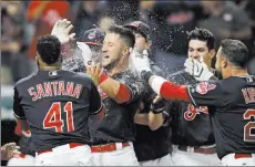  ?? Tony Dejak ?? The Associated Press Cleveland Indians catcher Yan Gomes, center, is mobbed by teammates after hitting a game-winning three-run home run off Colorado Rockies relief pitcher Greg Holland in the ninth inning on Tuesday in Cleveland.