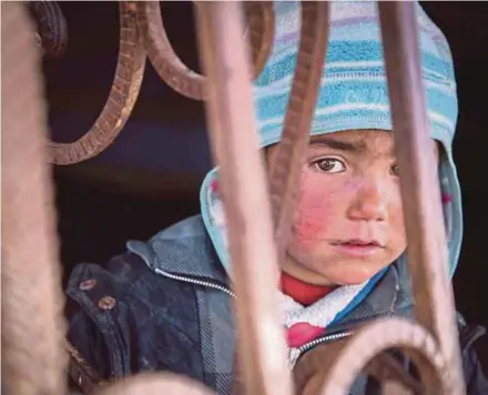  ?? AP PIC ?? A child looking out from an abandoned petrol station where he and his family live in Tel Abiad, Syria.