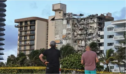  ?? (David Santiago/Miami Herald/TNS) ?? NEIGHBORS GAZE at the rubble at Champlain Towers South Condo in Surfside, Florida, a part of which collapsed in June.