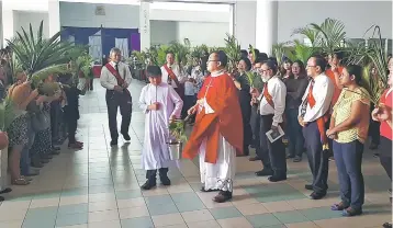  ??  ?? Father Vincent Sta (centre) blessing the palm branches at a church entrance during Palm Sunday which is held the Sunday before Easter Sunday.