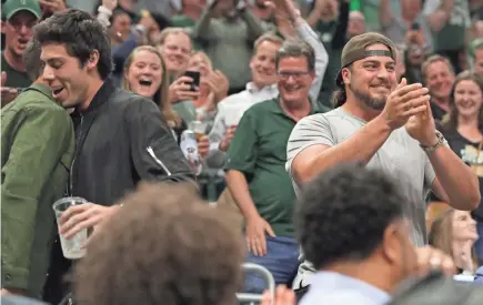  ?? MARK HOFFMAN/MILWAUKEE JOURNAL SENTINEL ?? Milwaukee Brewers outfielder Christian Yelich, left, basks in the cheers of fans after chugging a beer while Green Bay Packers offensive tackle David Bakhtiari, right, applauds during Game 5 between the Milwaukee Bucks and the Toronto Raptors Thursday at Fiserv Forum. The Bucks started fast but fizzled late and trail the series, 3-2. More coverage on pages 10A and 1B, and at jsonline.com.