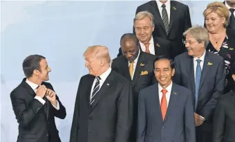  ?? POOL PHOTO ?? President Trump stands on the edge of the G- 20 leaders speaking to French President Emmanuel Macron as they prepared for the “family photo” during the summit Friday in Hamburg.