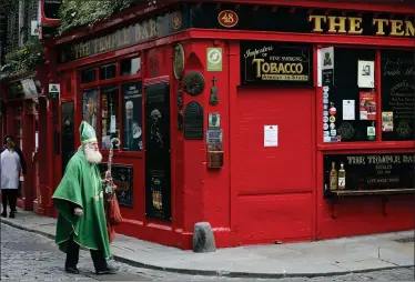  ?? PETER MORRISON — THE ASSOCIATED PRESS ?? A man dressed as St. Patrick walks past a closed Temple bar March 16in Dublin city centre. All pubs in the Republic of Ireland closed late Sunday to try and tackle the spread of COVID-19.