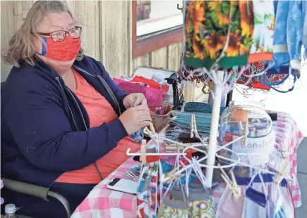  ?? SARAH KLOEPPING/USA TODAY NETWORK-WISCONSIN ?? Sandy Nimmo, owner of SENsationa­l handcrafts, makes free face masks outside her store in Sturgeon Bay earlier this summer.