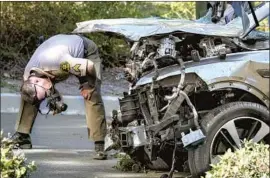  ?? Ringo H.W. Chiu Associated Press ?? A LAW ENFORCEMEN­T OFFICER looks over Tiger Woods’ damaged 2021 Genesis GV80 following the rollover accident Tuesday in Rancho Palos Verdes.