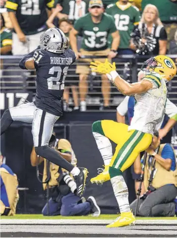  ?? JEFF LEWIS AP ?? Raiders’ Amik Robertson seals game with an intercepti­on on a pass intended for Christian Watson (right).