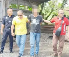  ??  ?? One of the suspects arrested by the CID team being brought to Miri Central Police Station to facilitate investigat­ion.