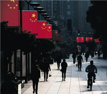  ?? JOHANNES EISELE / AFP / GETTY IMAGES ?? People walk along a pedestrian shopping street in Shanghai, China, a country where population growth has been slowing for decades, and in 2016 was at a mere 0.54 per cent. The World Bank estimates the population will peak in about 10 years.