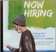  ?? TONY DEJAK — THE ASSOCIATED PRESS ?? A man walks past a “Now Hiring” sign on a window at Sherwin Williams store, Friday, Feb. 26, 2021, in Woodmere Village, Ohio. Massive fraud in the nation’s unemployme­nt system is raising alarms.