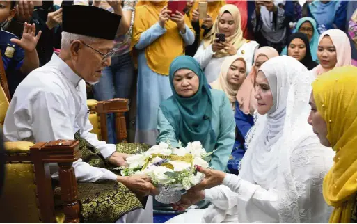  ??  ?? Sealing the deal: Hussain handing over the dowry to Kamsiah during their marriage ceremony at the al-Barakah Education Centre in Kampung Manjoi, Ipoh. — Bernama