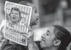  ??  ?? A woman plays with her son as she holds an illustrati­on of former first lady Imelda Marcos behind jail bars during a rally outside the special anti-graft Sandiganba­yan court in Manila. (AP)