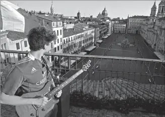  ?? ALBERTO LINGRIA / REUTERS ?? Iacopo Mastrangel­o plays his guitar while looking over Piazza Navona on Saturday, as Italians remain under lockdown to prevent the spread of the novel coronaviru­s.