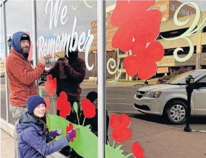  ?? CAROLYN DRAKE/THE GUARDIAN ?? Commercial artists Starla Wilson and Ryan Wilson of Shiny Paint bring the message of Remembranc­e Day to P.E.I.’s capital as they decorate a business window this past Sunday afternoon. They were hired by Business Technology Consulting on Queen Street.