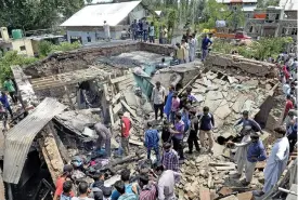  ?? (AFP) ?? Villagers gather near a damaged house where two suspected rebels were killed, near Srinagar on Tuesday