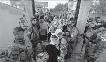  ?? Safin Hamed
AFP/Getty Images ?? KURDISH peshmerga forces help Yazidis arriving at a medical center near Kirkuk in northern Iraq. An Iraqi lawmaker confirmed that 217 freed Yazidis, including 60 children, had arrived in Kirkuk province.