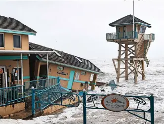  ?? Paul Hennessy/SOPA Images/REX/Shuttersto­ck ?? > Waves crash near a damaged building and lifeguard tower in Daytona Beach Shores – Q3