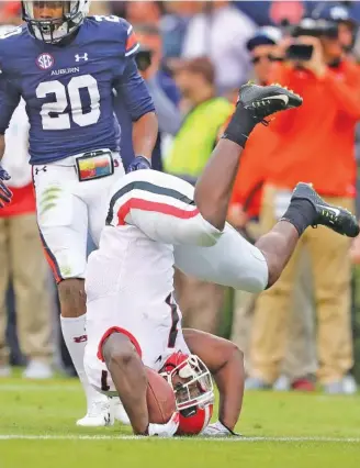  ?? THE ASSOCIATED PRESS ?? Georgia tailback Sony Michel is upended by Auburn defenders as defensive back Jeremiah Dinson looks on during the first half of the host Tigers’ 40-17 win Saturday in Auburn, Ala.