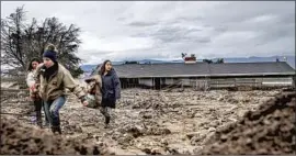  ?? Noah Berger Associated Press ?? PEOPLE in a Salinas neighborho­od carry belongings from a home damaged by a mudslide Wednesday. Debris flows are a danger in areas scarred by wildfires.