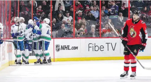  ?? — GETTY IMAGES ?? Elias Pettersson of the Canucks is somewhere in that mob, being congratula­ted for his second of three goals Wednesday in Ottawa. The dejected Senator is Christian Wolanin.