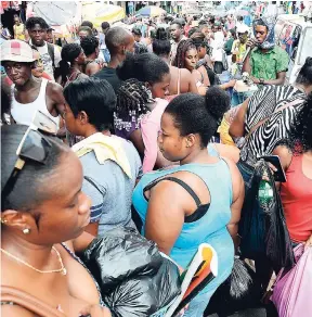  ??  ?? The sidewalk beauty salons were in full swing in downtown Kingston, yesterday, two days before Christmas, and a woman is enhancing her lashes for the holiday. Shoppers rub shoulders as Beckford Street was transforme­d into a huge bazaar.