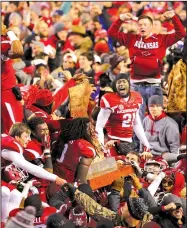  ?? Arkansas Democrat-Gazette file photo ?? Arkansas football players and Razorbacks fans celebrate the 2014 victory over LSU in Fayettevil­le and winning the Golden Boot.