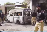  ?? ?? KARACHI: Police inspect a site around damaged vehicles following a suicide bombing near the Confucious Institute affiliated with the Karachi University, in Karachi. —AFP