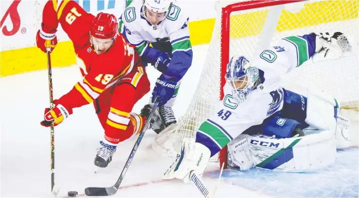  ?? SERGEI BELSKI / USA TODAY SPORTS ?? Calgary's Matthew Tkachuk and Vancouver's Quinn Hughes battle in front of Braden Holtby. The goalie is confident the Canucks' PK will get better.