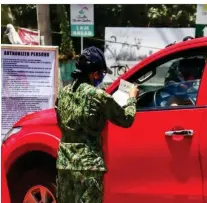  ?? (Sunstar Photo/Amper Campana) ?? STRICT MEASURES. A policewoma­n manning the border checkpoint between the cities of Cebu and Talisay in Brgy. Bulacao checks the papers of a passing vehicle owner to determine if the driver has permission to enter the province.