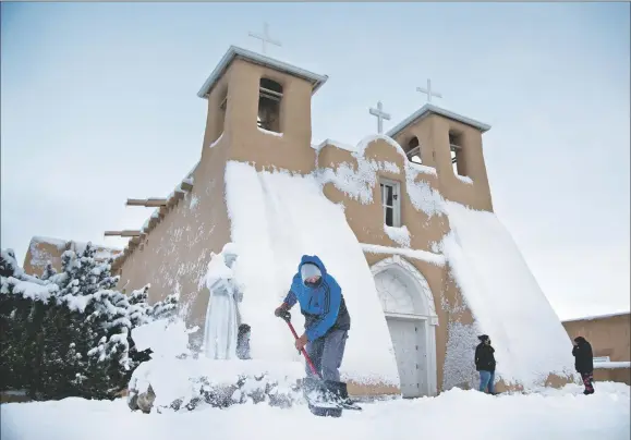  ??  ?? Dolores Valerio of Ranchos de Taos, clears a pathway for parishione­rs attending Ash Wednesday mass (Feb. 17) at San Francisco de Asís Mission Church.