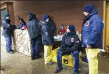  ?? KATHLEEN RONAYNE — THE ASSOCIATED PRESS ?? National Urban Search &amp; Rescue Response System Orange County CATF-5 team members Imelda Cordova, third from right, talks Andrew Ricker, and Craig Stevens, far right, as their team take cover from the rain in Paradise Friday.