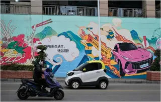  ?? PHOTO AFP ?? WIDESPREAD
This photo taken on Jan. 24, 2024 shows a mini electric vehicle and a motorcycle driving on a street in Liuzhou, in China’s Guangxi province. Small electric cars are proliferat­ing in southern China with their cheap and cheerful designs, which make them stand out in the lesser-known locales in China.