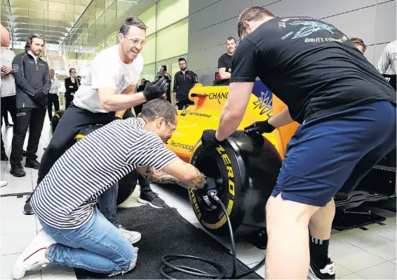  ?? PHOTO: GETTY IMAGES ?? Time for a change . . . Ben Smith urges on fellow All Blacks Aaron Smith (with wheel gun) and Dane Coles as they take part in a Formula One pit stop tyre change competitio­n during a team visit to the McLaren Technology Centre in Woking, England, yesterday.
