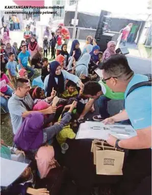  ??  ?? KAKITANGAN Petrosains memberi cenderamat­a kepada pelawat.