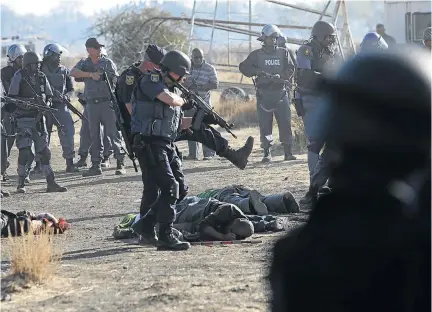  ?? / ALON SKUY ?? Injured workers and the bodies of dead striking miners lie on the ground following shooting by police at the Marikana mine near Rustenburg, North West.