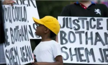  ?? SHABAN ATHUMAN — THE DALLAS MORNING NEWS VIA AP ?? “Young King” Solomon Grayson, 6, looks over at a sign that reads “You Could be Botham Shem Jean” during a Mothers Against Police Brutality candleligh­t vigil for Jean at the Jack Evans Police Headquarte­rs on Friday in Dallas. Authoritie­s are seeking a manslaught­er warrant for the Dallas police officer who shot and killed Jean after she said she mistook his apartment for her own, police said Friday.