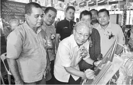  ??  ?? Masing signs on a plaque to launch the Tagang system while (from left) Aaron, Entili, Donny, Pengiran (right) and Alexander (second right) look on.