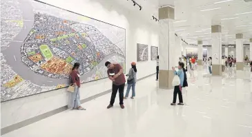  ?? WICHAN CHAROENKIA­TPAKUL ?? People take photos with a map of an old area of Bangkok inside the newly-opened Na Phra Lan tunnel near the Temple of the Emerald Buddha.