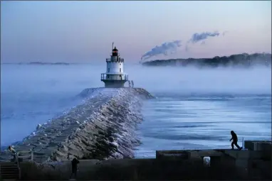  ?? ROBERT F. BUKATY — THE ASSOCIATED PRESS ?? A man walks on sea wall near Spring Point Ledge Light, Saturday, Feb. 4, 2023, in South Portland, Maine. The morning temperatur­e was about -10 degrees Fahrenheit.