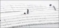  ?? CP PHOTO ?? Workers examine a hole in top of the Rogers Centre as the area around the CN Tower was closed off due to reports of falling ice Monday in Toronto.