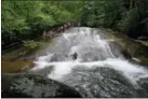  ?? HILLARY SPEED VIA AP ?? This photo shows two people riding down Sliding Rock, a natural waterslide located in the Pisgah National Forest, between Brevard, N.C., and the Blue Ridge Parkway. Known as “The Land of the Waterfalls,” Transylvan­ia County boasts more than 250 waterfalls that attract visitors every year.