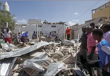  ??  ?? Somalis search for bodies amidst wreckage at the scene of a blast outside the compound of a district headquarte­rs in the capital Mogadishu, Somalia, Sunday. A Somali police o cer says a number of people are wounded after a suicide bomber detonated an explosives-laden vehicle at a checkpoint outside the headquarte­rs after being stopped by security forces. AP PHOTO/FARAH ABDI WARSAMEH MUKWAZHI