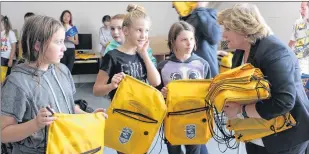  ?? SAM MCNEISH/THETELEGRA­M ?? The Telegram’s Newspapers In Education program co-ordinator Carol Wadden hands out knapsacks to Grade 6 students (from left) Rachael Hammond, Sarah Mcqueen and Charley Sandeman, who were on hand for the introducti­on of the NASCAR’S Accelerati­on Nation...