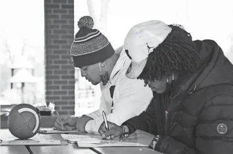  ?? MATTHEW DAE SMITH/LANSING STATE JOURNAL ?? East Lansing senior football players Anthony Boyd, left, and Andrel Anthony Jr. sign letters of intent to play at the college level Wednesday at Patriarche Park in East Lansing. Boyd will play at Michigan State, and Anthony at Michigan.