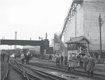  ?? L R Freeman ?? Deptford Wharf North signal box oversaw Grove Road level crossing, which extended across the expanse of sidings as they fanned out on to the wharves. Presumably any road traffic may have had a long wait for shunting activity to cease, but at least the railway provided a footbridge for pedestrian­s. With the stock of the rail tour visible beyond the footbridge, the signalman seems to be rather inundated with visitors. Weight restrictio­ns precluded the use of steam engines on the quayside, with ropes and power-operated capstans employed to move the wagons the distance between the shipping and a point where they could reach an engine or join a train.