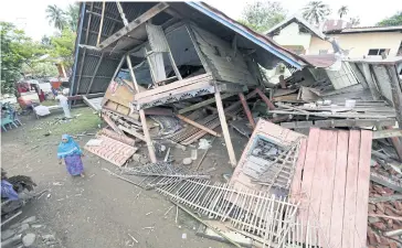  ??  ?? WHERE TO NOW?: An Acehnese woman passes collapsed buildings at Pangwa Village Meureudu, Pidie Jaya after an earthquake struck.