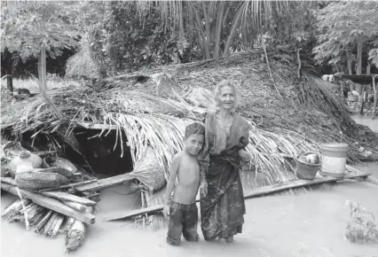  ?? FOTO: AFP ?? > Una anciana aldeana y su nieto frente a su casa dañada en la aldea de Haitimuk.