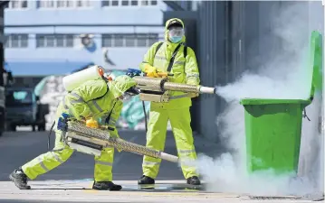  ??  ?? Volunteers in protective suits disinfect a factory with sanitising equipment in Huzhou, Zhejiang province.