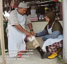  ??  ?? MD Jasmi membetulka­n kaki palsu sambil dibantu Norlida di kedai santan miliknya di pekan Air Mawang.